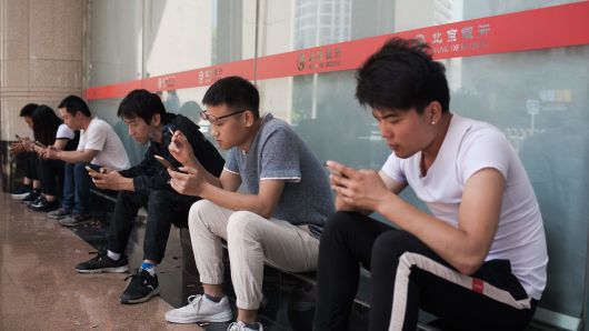 People use their mobile phones outside an office building in Beijing on May 24, 2018.? 